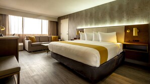 A hotel room with a large bed, a sofa, a desk, and a nightstand with lamps. - Atlantica Hotel Halifax (Halifax)