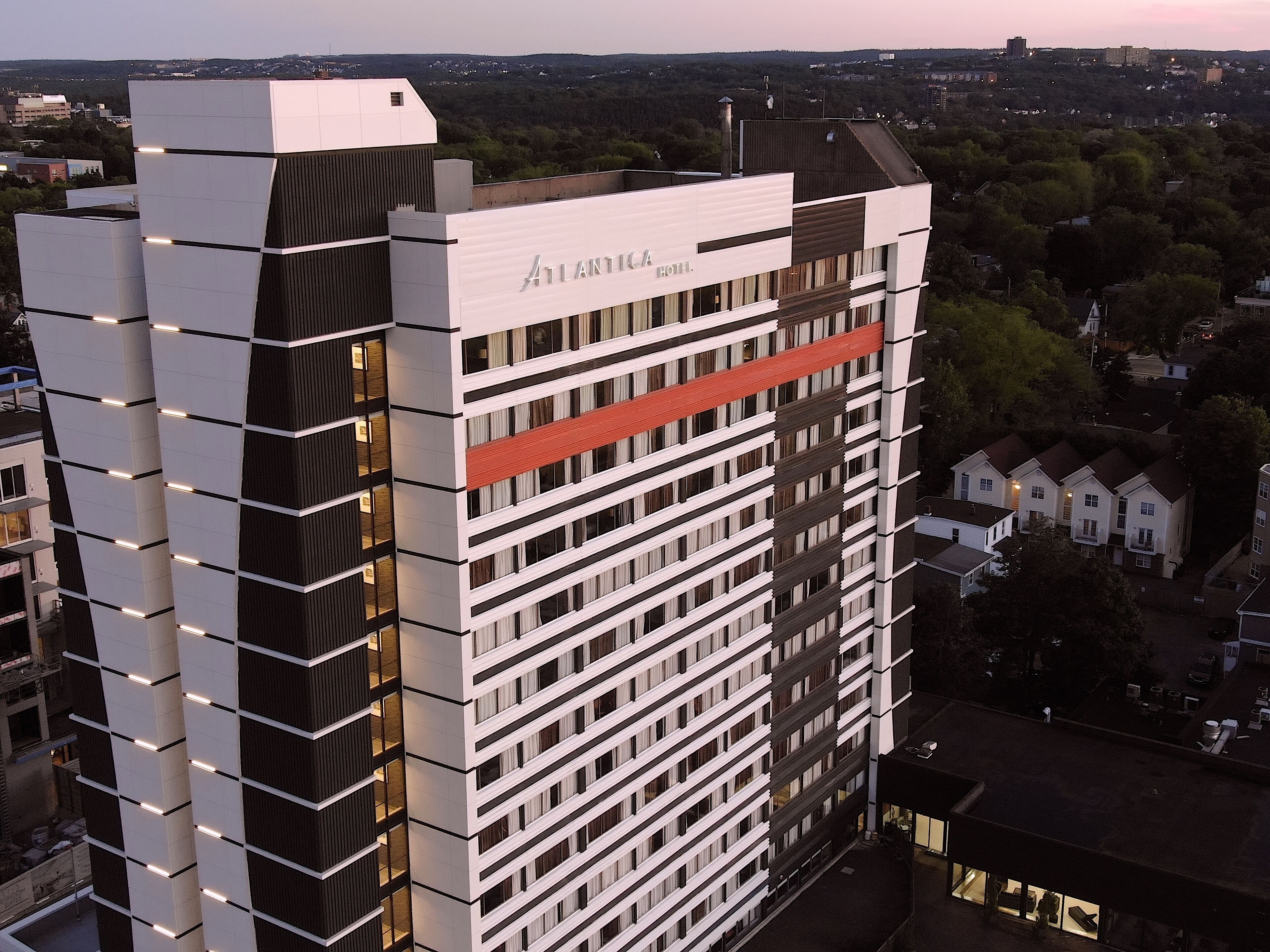 A modern hotel building with a prominent name sign, multiple floors, and a mix of window styles.