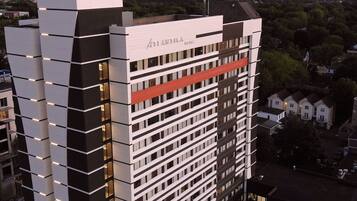 A modern hotel building with a prominent name sign, multiple floors, and a mix of window styles.