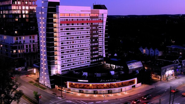 A multi-story hotel with a prominent "Atlantica Hotel" sign, a corner location with a visible entrance, and a parking area with cars. - Atlantica Hotel Halifax (Halifax)