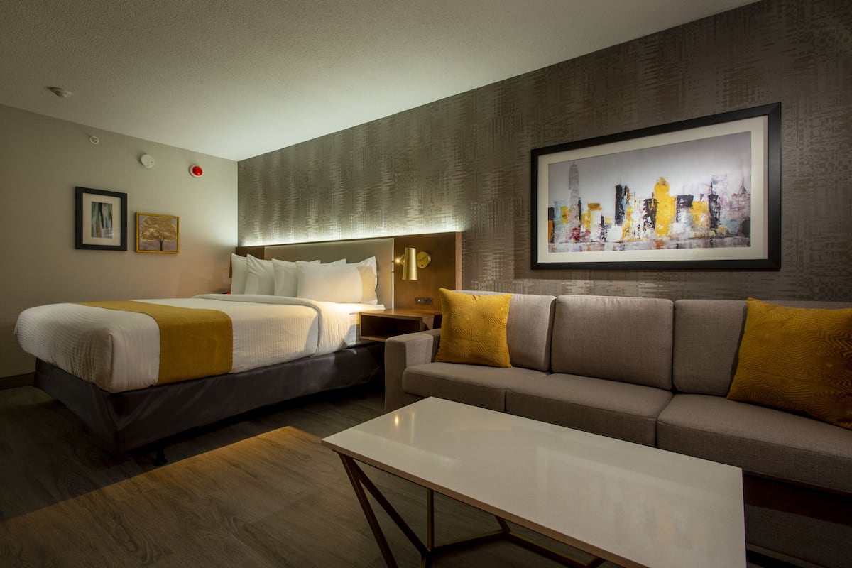 A hotel room with two beds, a sofa, a coffee table, and artwork on the walls.