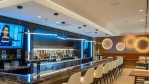A modern bar area with a marble countertop, white bar stools, and a variety of liquor bottles. - Atlantica Hotel Halifax (Halifax)