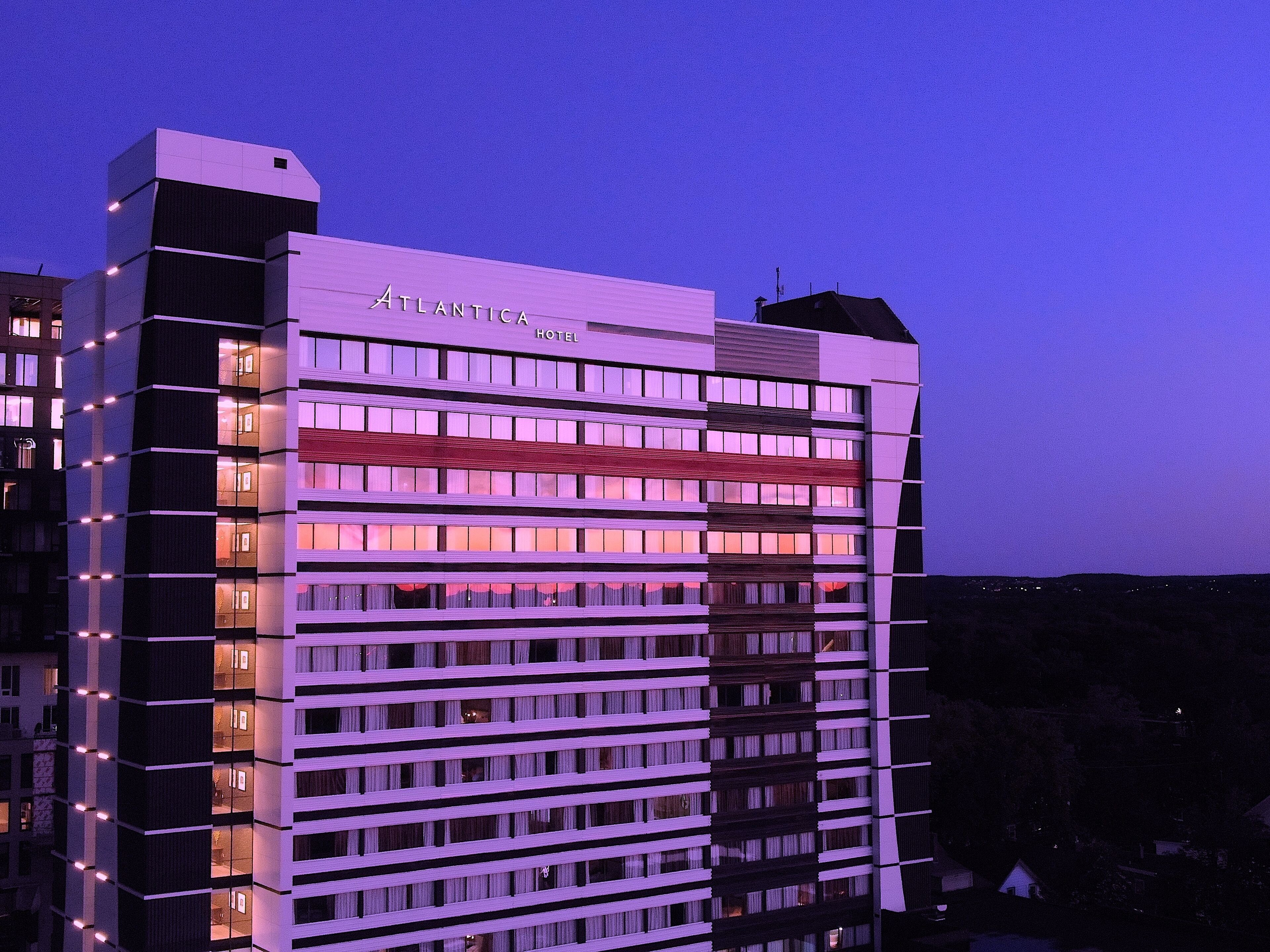 A multi-story hotel with a modern design, featuring a prominent "Atlantica Hotel" sign at the top.