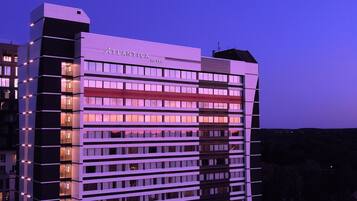 Un hotel de varios pisos con diseño moderno, destacando un llamativo letrero que dice "Atlantica Hotel" en la parte superior.