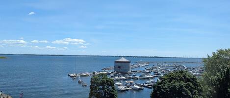 A marina with boats docked, a lighthouse, and a clear sky.