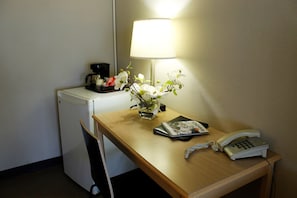 Relax in a compact room with a desk, refrigerator, and coffee maker.