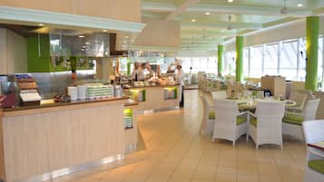 A spacious restaurant with a buffet counter, multiple dining tables, and chairs.