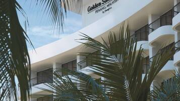 Voici l’extérieur du Golden Sands Resort à Penang, en Malaisie, qui présente une architecture moderne avec de nombreux balcons et des palmiers.