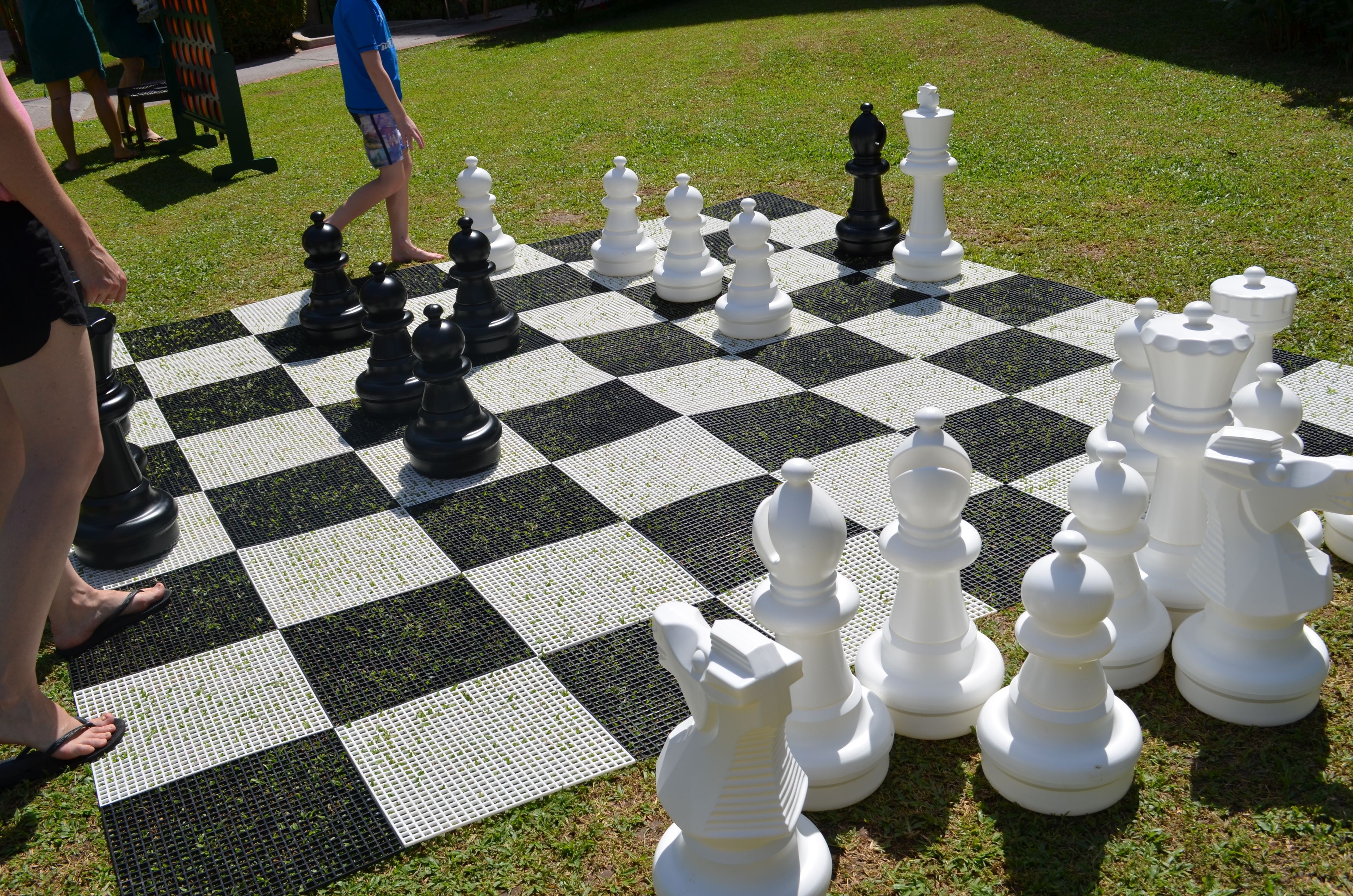 A large outdoor chessboard set up on a grassy area.