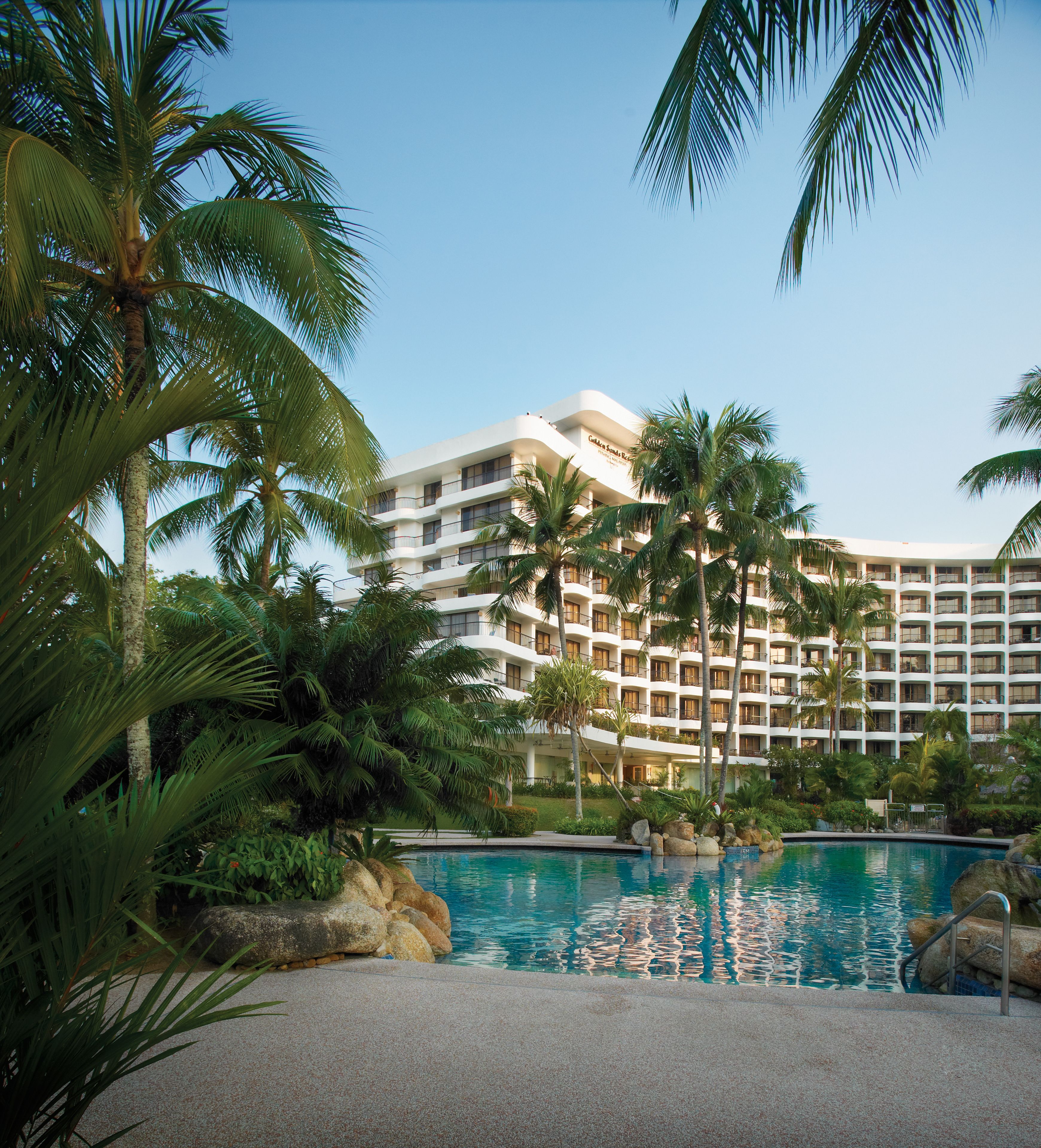 A resort with a pool, palm trees, and a multi-story building.