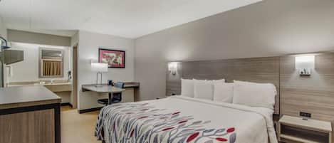 A hotel room with a bed, bedside table, desk, and a bathroom.