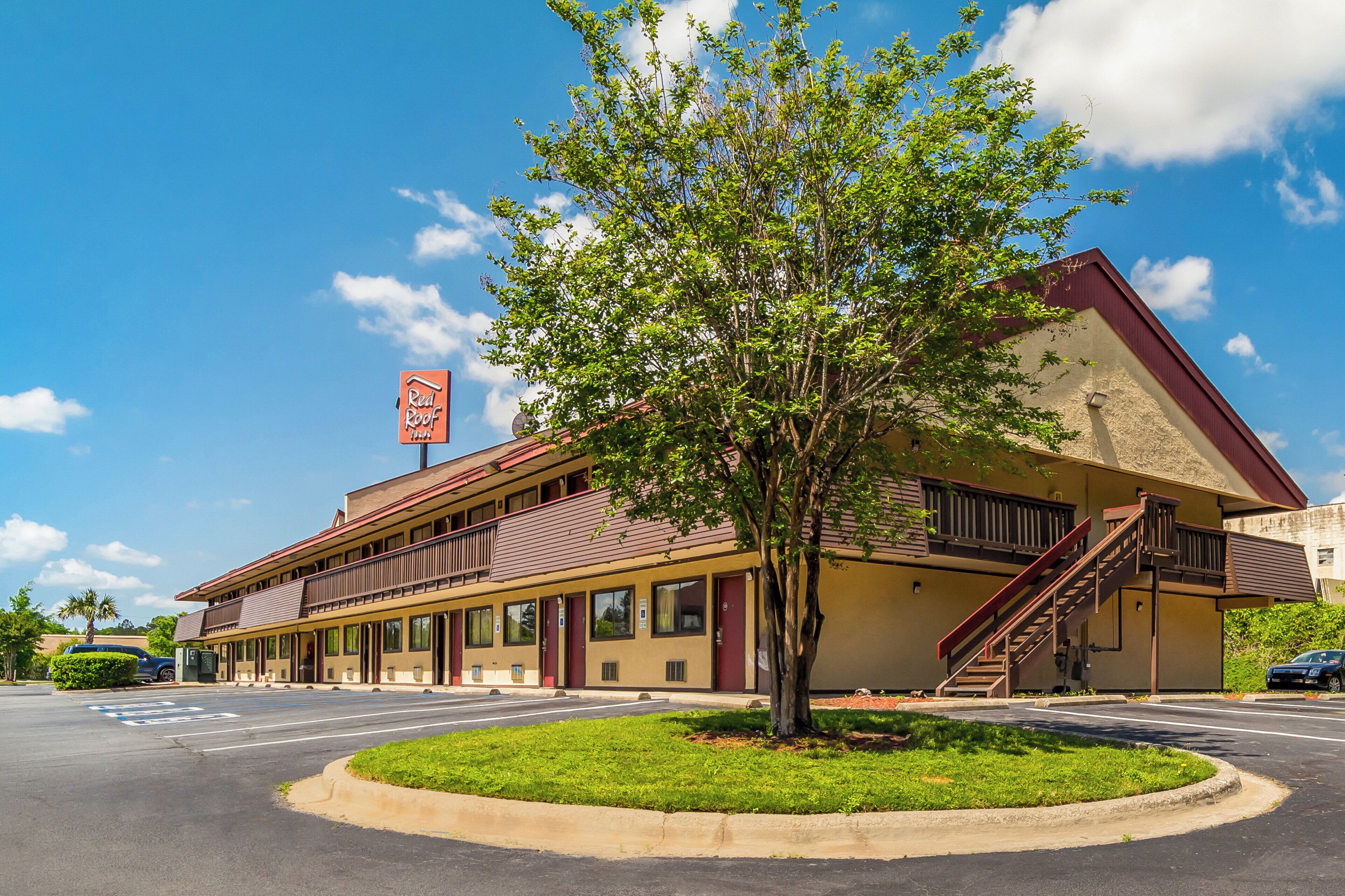 A two-story motel with a red roof and a sign that reads 'Red Roof.'