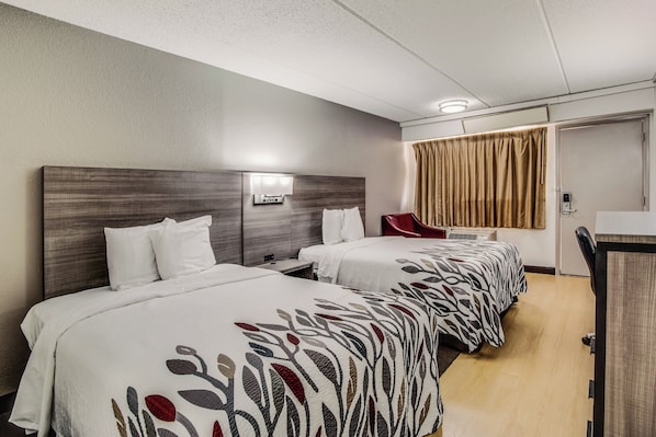 A hotel room with two beds, a desk, a chair, and a bathroom door. - Red Roof Inn Columbia East - Ft Jackson (Columbia)