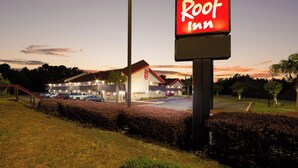 A Red Roof Inn sign with a parking lot and a building in the background.