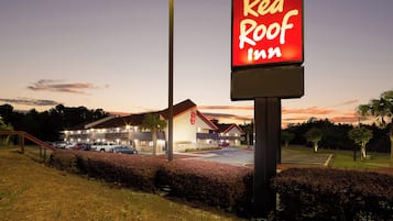 A Red Roof Inn sign with a parking lot and a building in the background.