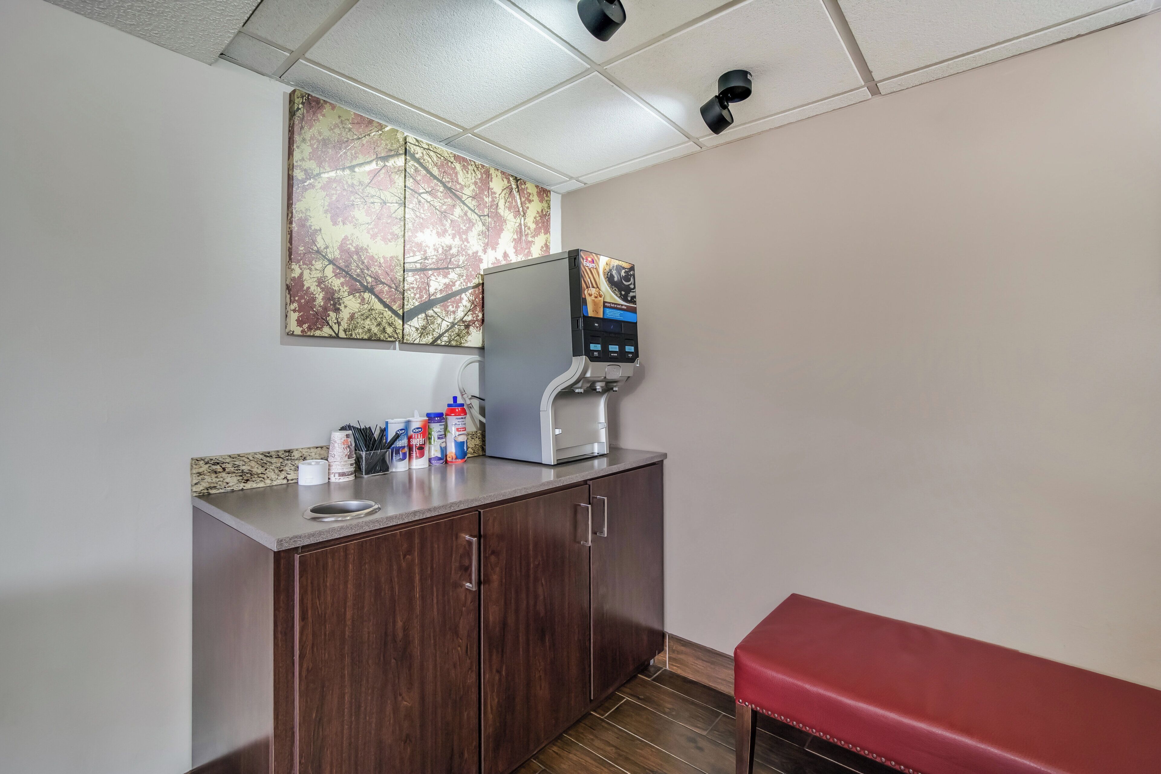 A kitchenette with a coffee machine, a refrigerator, and a countertop with various items.