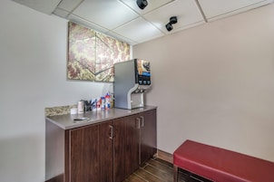 Una kitchenette equipada con cafetera, refrigerador y encimera con diversos objetos.