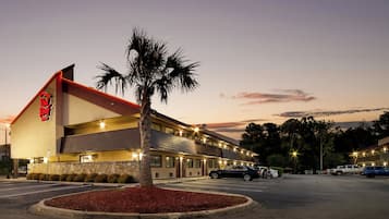 A motel with a red roof and a palm tree in front.