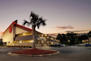 Un motel con techo rojo y una palmera frente a él.