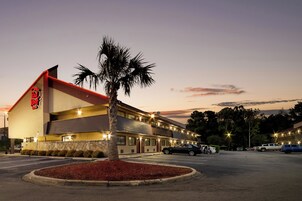 Un motel con techo rojo y una palmera frente a él.