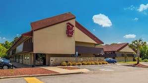 A Red Roof Inn with a two-story structure, a stone facade, and a parking lot.
