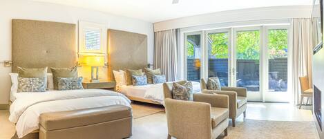 Amplia habitación con una cama grande, un sofá y una silla, con puerta corrediza de vidrio a un balcón.