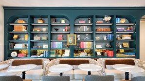 Una biblioteca con varias estanterías llenas de libros y objetos decorativos, un sofá y mesas.