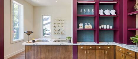 A modern kitchen with a marble countertop, wooden cabinets, and a patterned rug.