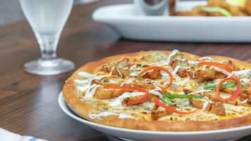 Une pizza garnie et un verre d’eau sur une table.