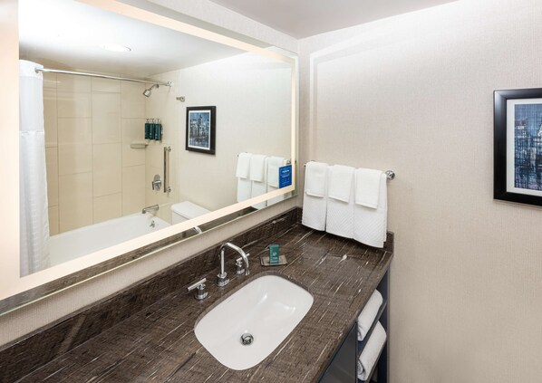 Un baño moderno con un espejo grande, un lavamanos y una ducha.
