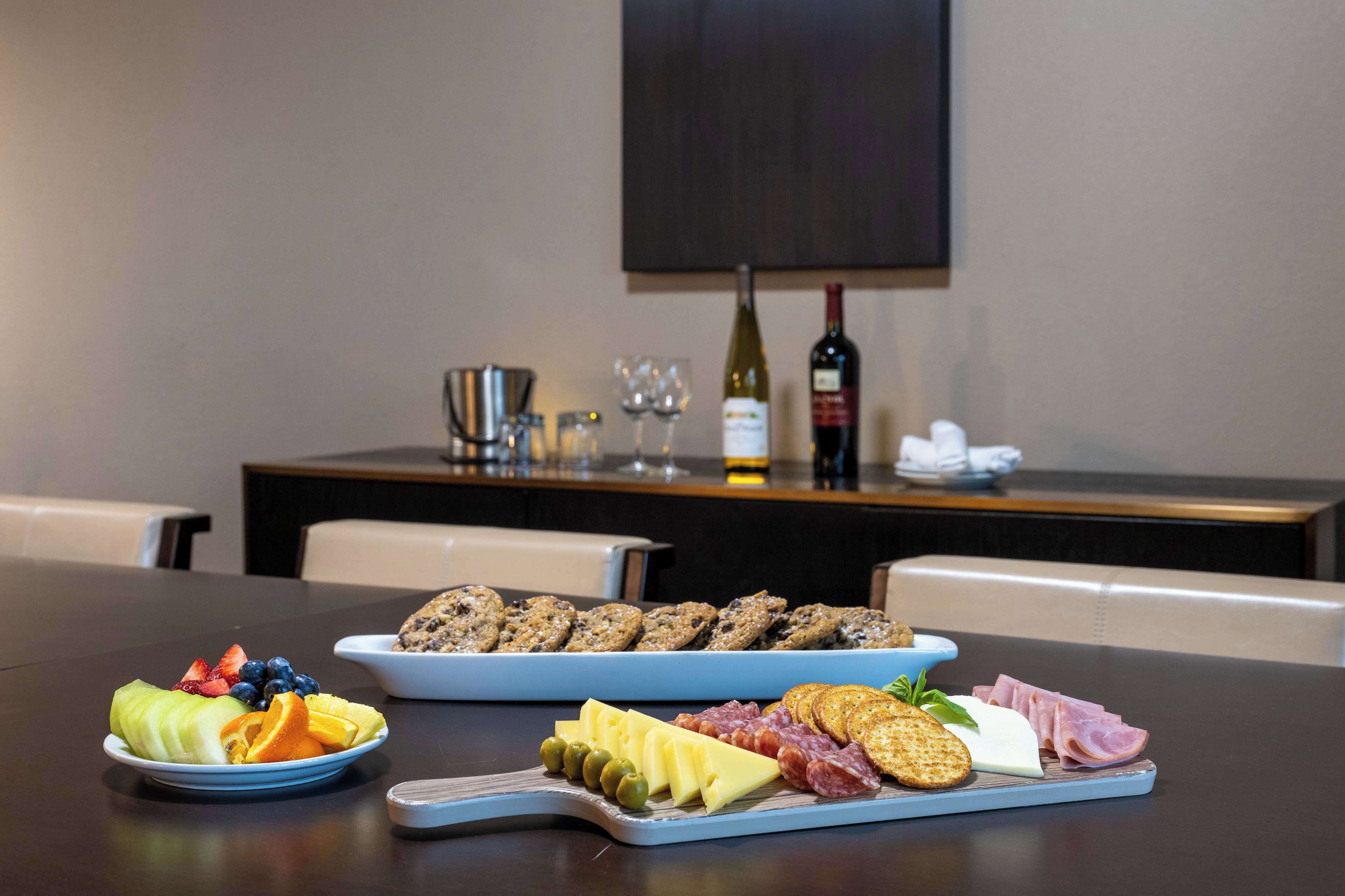 A table with a fruit platter, cheese and crackers, and a charcuterie board.