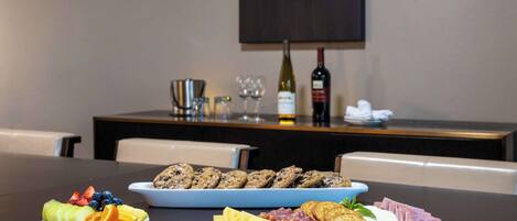 A table with a fruit platter, cheese and crackers, and a charcuterie board.