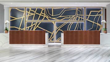 Un área de recepción con diseño moderno, que presenta un piso de mármol y una pared decorativa con motivos geométricos.