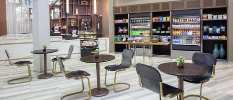 A modern coffee shop interior with seating arrangements, a menu board, and a variety of beverages and snacks.