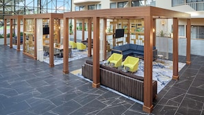 A modern indoor lobby with a glass facade, wooden partitions, and seating areas.