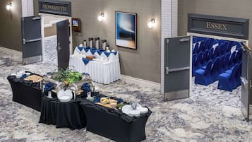 Vestíbulo de hotel con una mesa de buffet, zona de estar y señalización direccional para Monmouth y Essex.