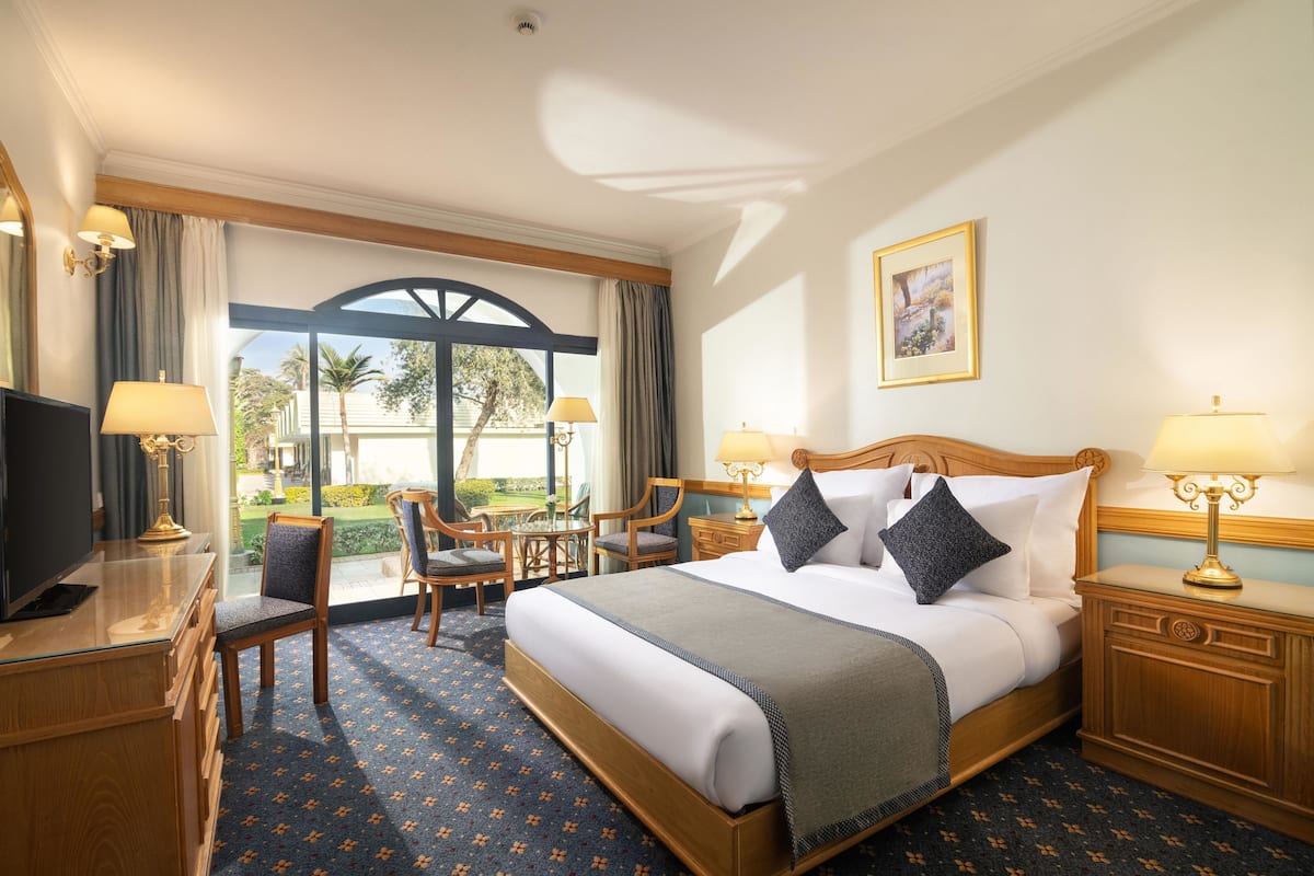 A hotel room with a bed, bedside tables, a desk, and a TV.