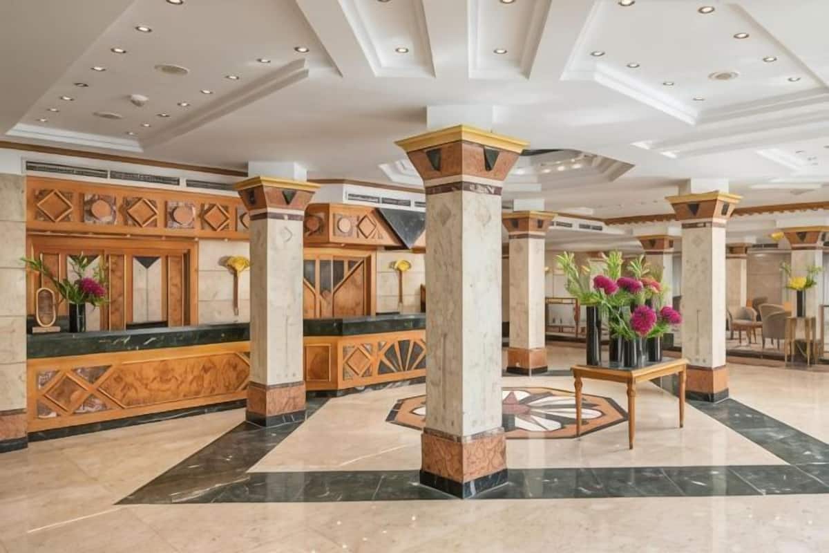 A lobby with marble floors, wooden reception desks, and columns.