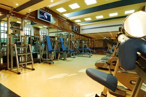 A gym with exercise equipment, a television screen, and a mirrored wall. - JAZ Pyramids Resort (Giza)