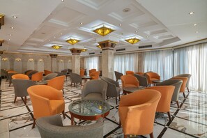 A spacious hotel lobby with multiple seating areas, a marble floor, and decorative ceiling lights. - JAZ Pyramids Resort (Giza)