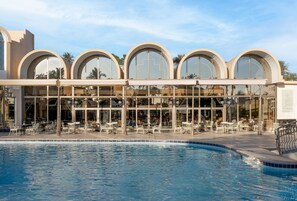 A hotel with a pool, outdoor seating, and large arched windows. - JAZ Pyramids Resort (Giza)