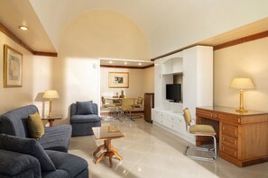 A living room with a sofa, a dining table, a TV, and a desk. - JAZ Pyramids Resort (Giza)