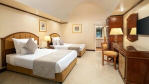 A hotel room with two beds, a desk, a chair, and a TV. - JAZ Pyramids Resort (Giza)