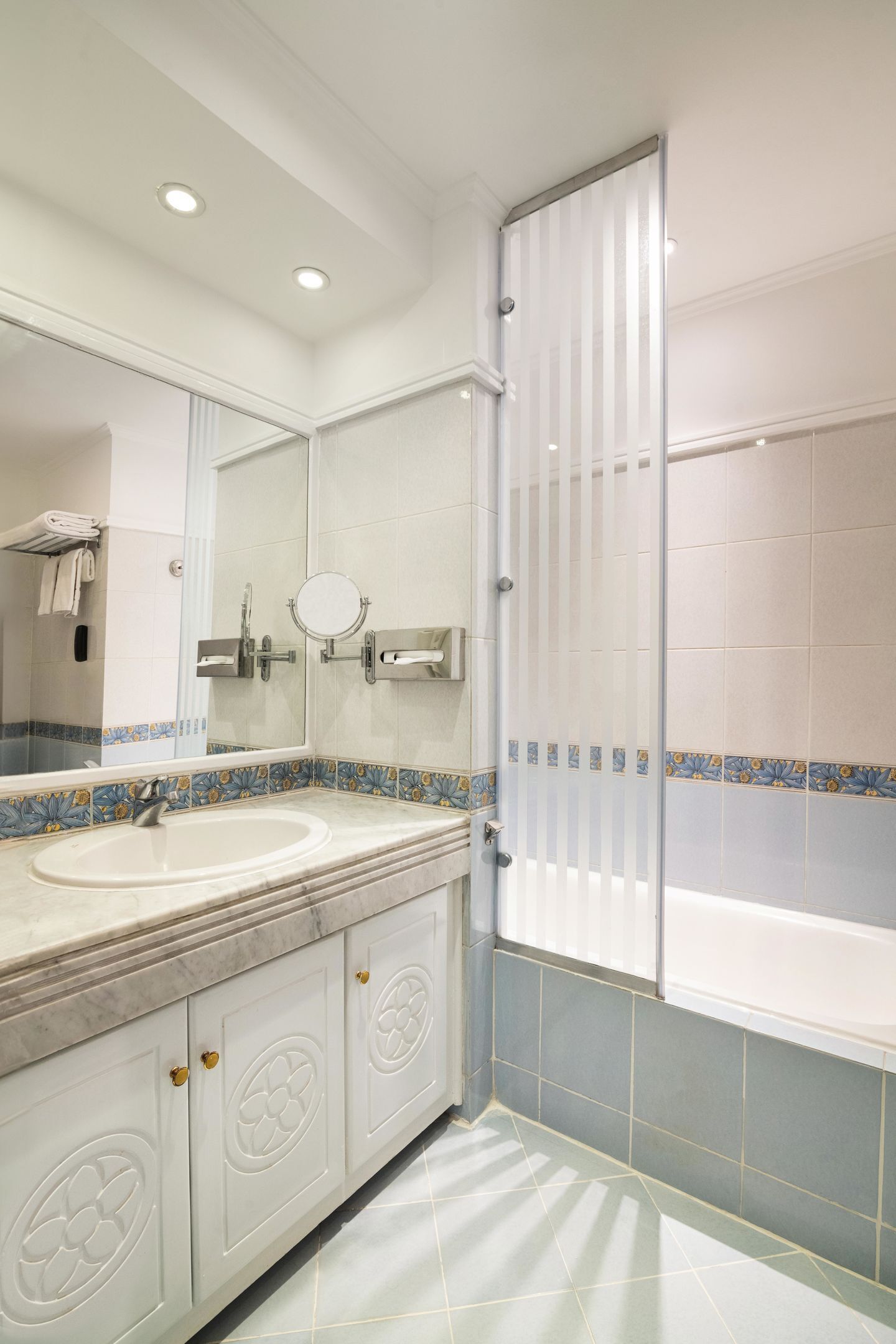 A bathroom with a double sink, a large mirror, a shower enclosure, and a tiled floor.