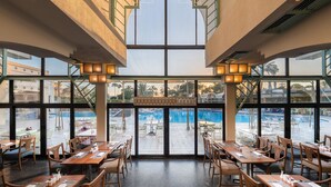 A restaurant with a view of a pool and outdoor seating.
