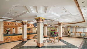 A spacious lobby with marble flooring, a reception desk, and decorative columns. - JAZ Pyramids Resort (Giza)