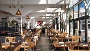 A spacious restaurant with high ceilings, wooden tables and chairs, and large windows allowing natural light. - JAZ Pyramids Resort (Giza)