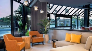 A modern lounge area with a sofa, armchairs, and a small table. Large windows provide views of the outdoors. - DoubleTree by Hilton Hotel San Bernardino (San Bernardino)