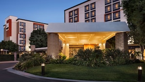 A modern hotel entrance with a covered walkway, landscaped garden, and a clear sky. - DoubleTree by Hilton Hotel San Bernardino (San Bernardino)
