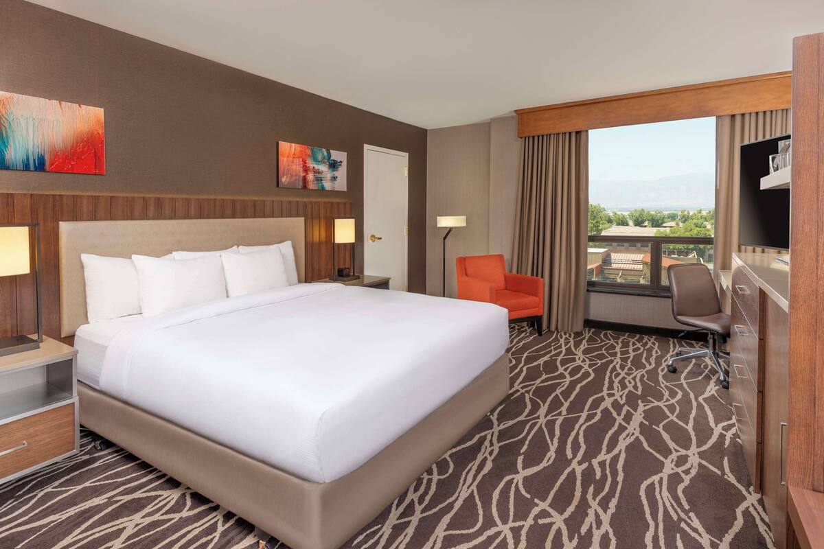 Une chambre d’hôtel avec un grand lit, un bureau, une chaise et une vue sur la ville.